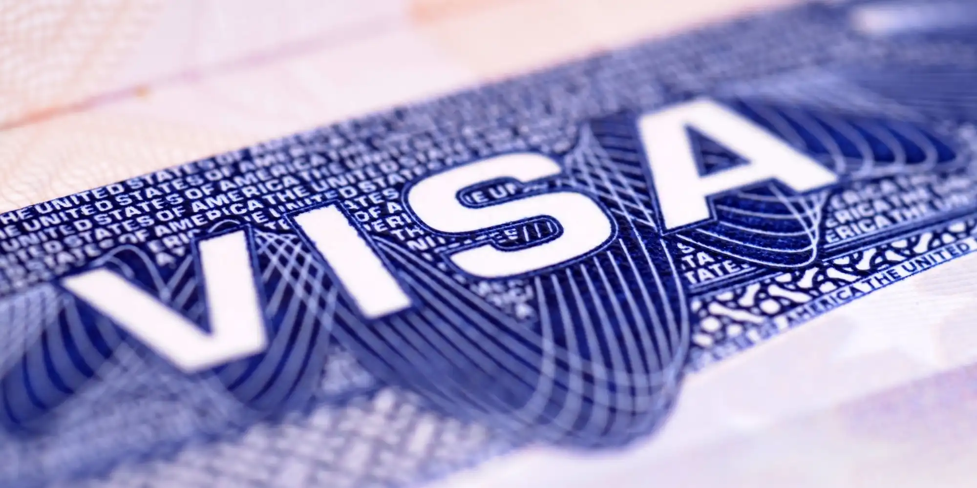 In the center of the image, we can see the word "VISA" clearly visible, with the text "UNITED STATES OF AMERICA" above and below it, indicating that this is a visa for the United States. The background of the visa is dark blue with an intricate line design that may represent security checks or tamper-evident features. Overall, the image highlights the importance of the visa and its role as an international travel document.
