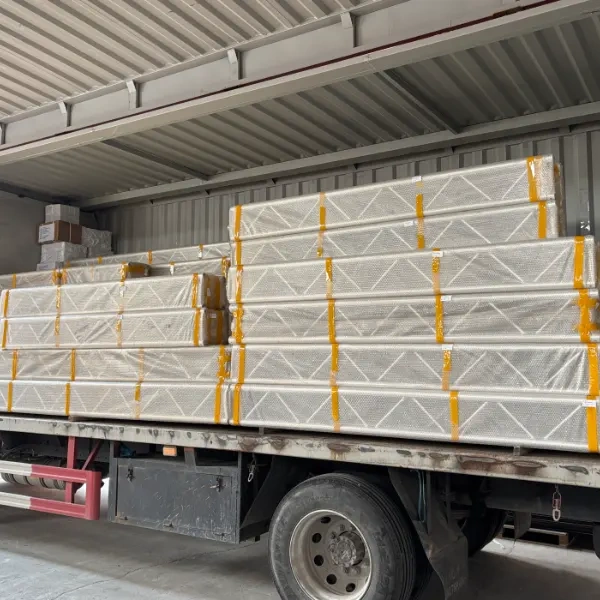 A truck loaded with stacks of aluminum alloy trusses, each wrapped in double - layer bubble film and secured with yellow straps, ready for delivery in an industrial warehouse setting.