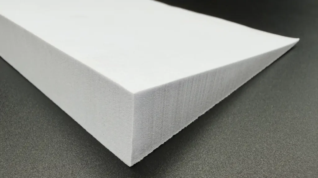 Close-up of the smooth glossy surface and sharp edges of a bevel-cut white EVA foam wedge