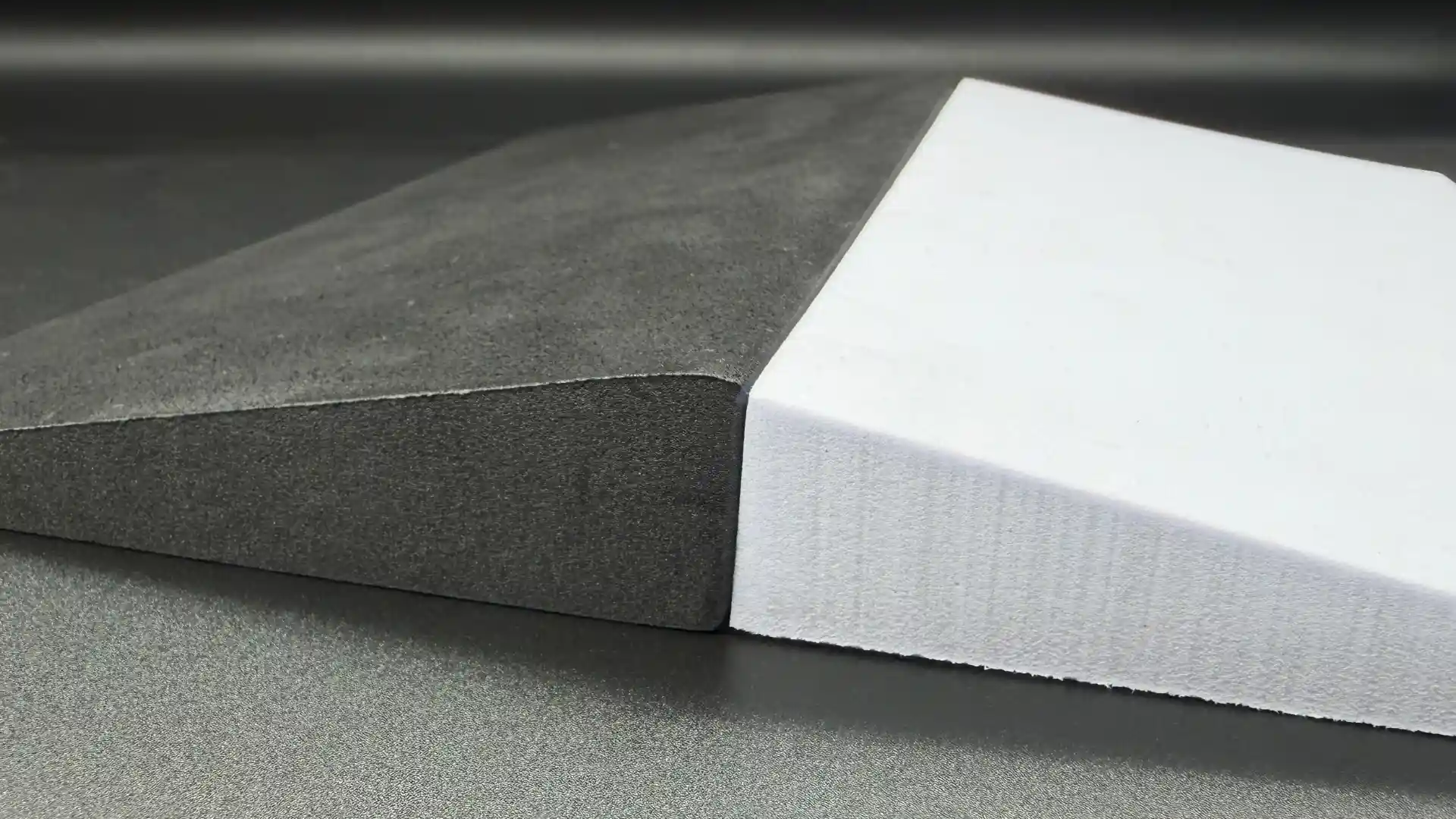 Black CNC wire-cut EVA foam wedge with rounded plush edges beside a white bevel-cut wedge with sharp smooth edges